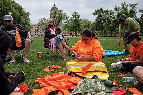JESSICA LEE / WINNIPEG FREE PRESS

Martha Paul (in orange) makes tobacco ties May 27, 2023 in the park. A dozen community members gathered at Memorial Park May 27, 2023, to remember the anniversary of the day in 2021 when 215 unmarked children’s graves were found in Canada.

Stand up