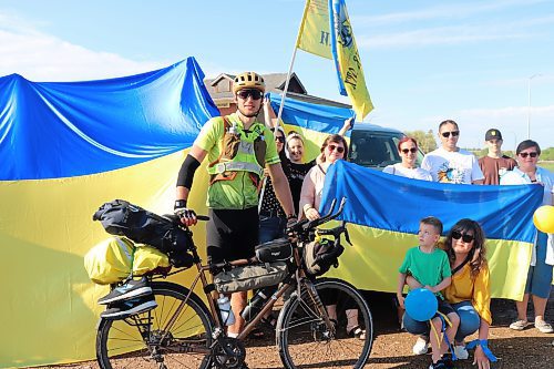 Dariy Khrystyuk poses for a photo with members of Brandon's Ukrainian community at Dinsdale Park after arriving in the city Monday evening. Khrystyuk has been travelling across the country on his bike since May 1 to raise money to help rebuild Ukrainian infrastructure that has been damaged or destroyed during the war. (Kyle Darbyson/The Brandon Sun)