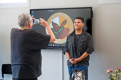 Mike Deal / Winnipeg Free Press
Orlando Harper, student and artist who helped design the school logo, has his photo taken by the school logo during the opening ceremony for Niiwin Minisiwiwag school, located at 383 Selkrik Avenue.
The Indigenous Education Caring Society is unveiling a new alternative school campus for First Nations, Metis and Inuit learners who've become disengaged with school in a bid to re-capture their attention, re-engage them and support them to graduate. The special North End site called, Niiwin Minisiwiwag, located at 383 Selkrik Avenue, is run via MOU/partnership with WSD, will support teens to complete their high school education. The aim is to find 'inactive students' (students that WSD receives funding for, but who have become lost in the system and don't currently attend classes). It's no secret COVID has worsened attendance in recent years. This project is a grassroots effort to make a dent in the issue of chronic absenteeism. The society is an initiative between Ma Mawi Wi Chitata Centre, Ndinawemaaganag Endawaad and the Community Education Development Association (CEDA). The newly-finished building was funded by a $500K grant from the Winnipeg Foundation, and grants from an anonymous donor and Sill Foundation, City of Winnipeg donated the land. We are getting an exclusive preview because of our ed coverage. 
See Maggie story
230530 - Tuesday, May 30, 2023.