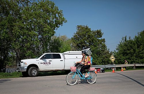 JESSICA LEE / WINNIPEG FREE PRESS

A biker rides past workers in Point Douglas May 25, 2023 who are testing the river for benzines.

Reporter: Julia-Simone Rutgers