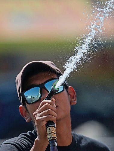 Martin Vega, an employee with Rick's Concessions, sprays water on the side of a booth on a hot Monday morning at the Keystone Centre parking lot, the site of the Manitoba Winter Fair which opens on Wednesday afternoon. (Matt Goerzen/The Brandon Sun)