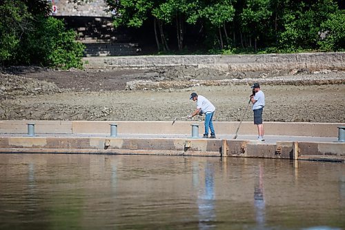 Mike Deal / Winnipeg Free Press
Heins Dawoodharry and Vitalii Maksymiv with The Forks shovel mud off the walkway at the edge of the Assiniboine River at The Forks Tuesday morning.
230606 - Tuesday, June 06, 2023.