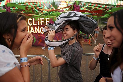 07062023
Olivia Relf uses a friend&#x2019;s backpack to shield herself from the rain while waiting in line for a midway ride during the opening night of the 2023 Manitoba Summer Fair at the Keystone Centre on a hot and stormy Wednesday night. (Tim Smith/The Brandon Sun)