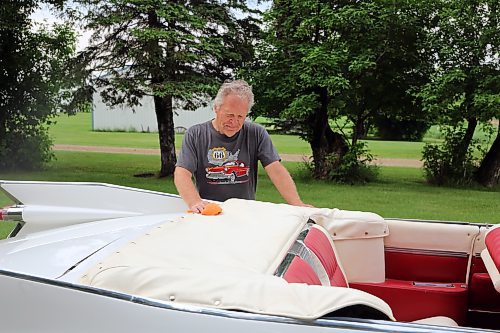 Elwin Kettner wipes of the morning dew on the top of his 1959 Cadillac 2-door convertible, near his his wife Elaine's home northwest of Brandon on Thursday. (Michele McDougall/The Brandon Sun)  