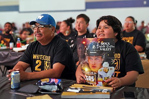Karla Bunn holds a poster featuring Vegas Golden Knights player Zach Whitecloud of Sioux Valley Dakota Nation while watching Game 3 of the Stanley Cup Final between the Golden Knights and the Florida Panthers with Rollie Bunn at a Stanley Cup viewing party for community members at Sioux Valley on Thursday evening. The event featured a barbecue supper, cake and the game broadcast on two big screens. For a story on the Sioux Valley event, turn to Page B1. (Tim Smith/The Brandon Sun)