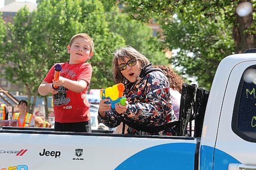 Some Travellers' Day Parade participants keep the crowd hydrated during a warm but breezy morning in downtown Brandon. (Kyle Darbyson/The Brandon Sun)