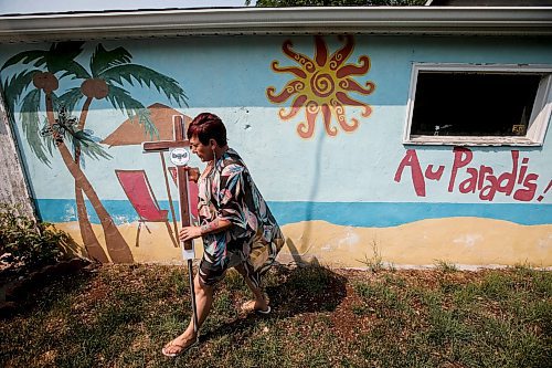 JOHN WOODS / WINNIPEG FREE PRESS
Lise Leveille, widow of Denis L&#x2019;Heureux who was killed when his motorcycle hit wet mud on a highway September 24/22, carries a roadside cross for Denis as she walks past a mural she painted for their wedding at their Winnipeg home, Monday, June 12, 2023. Leveille is working to get MB govt to make it law that signs must be posted when construction/farm debris is on the road surface.

Reporter: kitching
