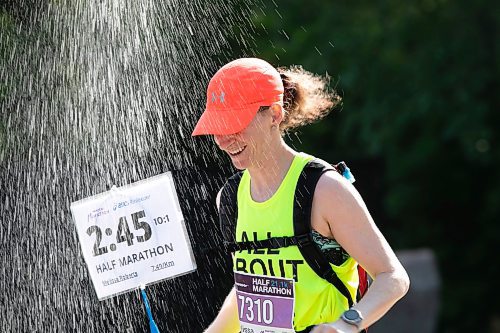 BROOK JONES / WINNIPEG FREE PRESS
Melissa Roberts, who is from Brandon, Man., runs under a makeshift shower at a volunteer water station run by Eastman Flames U14 and U16 ringette teams near Crescent Drive Park, while competing in the half marathon at the Manitoba Marathon in Winnipeg, Man., Sunday, June 18, 2023. Roberts was a pace rabbit for the 2:45 half marathon runners. 