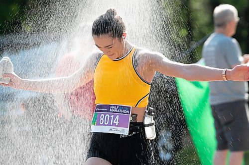 BROOK JONES / WINNIPEG FREE PRESS
Julia Mertins, who is from Niverville, Man., runs under a makeshift shower at a volunteer water station run by Eastman Flames U14 and U16 ringette teams near Crescent Drive Park, while competing in the half marathon at the Manitoba Marathon in Winnipeg, Man., Sunday, June 18, 2023. 