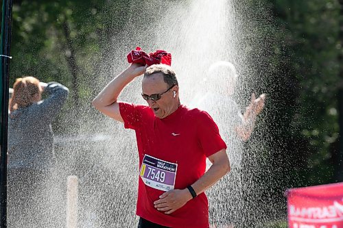 BROOK JONES / WINNIPEG FREE PRESS
Joe Urbanowich, who is from Winnipeg, Man., runs under a makeshift shower at a volunteer water station run by Eastman Flames U14 and U16 ringette teams near Crescent Drive Park, while competing in the half marathon at the Manitoba Marathon in Winnipeg, Man., Sunday, June 18, 2023. 