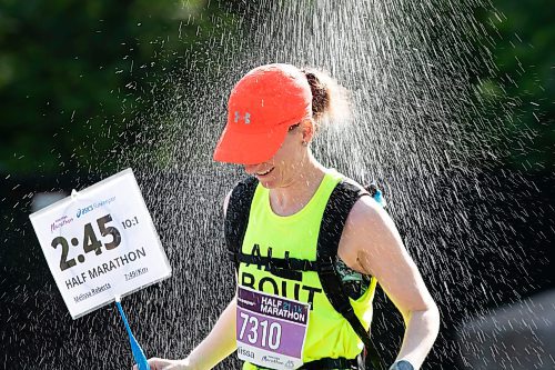 BROOK JONES / WINNIPEG FREE PRESS
Melissa Roberts, who is from Brandon, Man., runs under a makeshift shower at a volunteer water station run by Eastman Flames U14 and U16 ringette teams near Crescent Drive Park, while competing in the half marathon at the Manitoba Marathon in Winnipeg, Man., Sunday, June 18, 2023. Roberts was a pace rabbit for the 2:45 half marathon runners.
