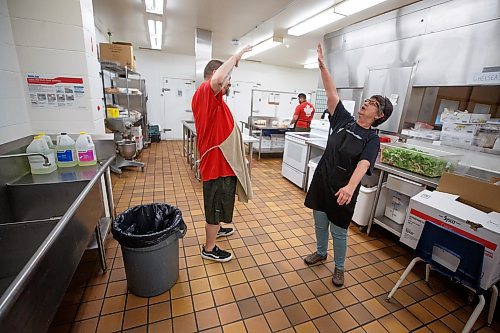 Mike Deal / Winnipeg Free Press
Roger West and Heather Wade work as a team and celebrate as a team in the kitchen at 324 Logan Avenue early Tuesday morning. Employed by Community Helpers Unite, an organization that employs around six to eight people who cook and prepare food and distribute them, for free,  to various organizations such as Main St Project.
230620 - Tuesday, June 20, 2023.