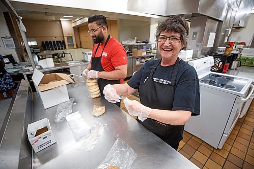 Mike Deal / Winnipeg Free Press
Kashish Kashish (left) and Heather Wade (right) portion out bagels in the kitchen at 324 Logan Avenue early Tuesday morning. Employed by Community Helpers Unite, an organization that employs around six to eight people who cook and prepare food and distribute them, for free,  to various organizations such as Main St Project.
230620 - Tuesday, June 20, 2023.