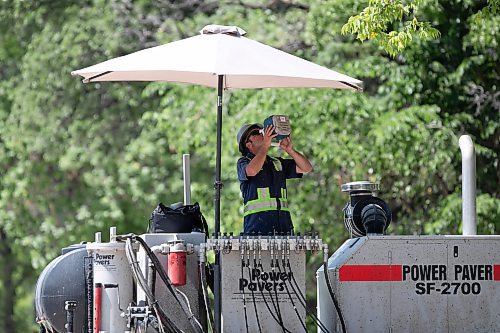 BROOK JONES / WINNIPEG FREE PRESS
Rui Tavares, who works for Bayview Construction Ltd., quenches his thirst and finds shade under a giant umbrella on a hot day in Winnipeg, Man., Tuesday, June 20, 2023. Tavares is operates a concrete forming machine along Jubillee Avenue.  