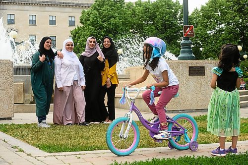 Mike Sudoma/Winnipeg Free Press
A young cyclist bikes by as a family poses for a photo with the fountain on the south grounds of the Manitoba Legislative Building Tuesday evening
June 20, 2023