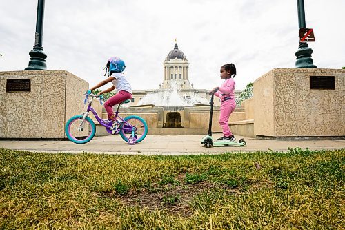 Mike Sudoma/Winnipeg Free Press
Two children scoot and bike past the fountains along the southern grounds of the Manitoba Legislature around 715 pm Tuesday
June 20, 2023