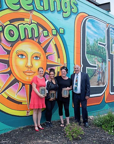 Mike Thiessen / Winnipeg Free Press 
L-R: Kristi Meek, president and executive director of the Asssiniboia Chamber of Commerce; Morgan Biggs and Jen Mosienko, artists of &#x201c;100 Years of St. James&#x201d;; and Tom Ethans, executive director of Take Pride Winnipeg. The mural, winner of the 2023 Mural of the Year award, can be seen at 1737 Portage Avenue, showcasing the history of the St. James community. The Mural of the Year has been run for the past 22 years by Bob Buchanan, who passed away last week. For Cierra Bettens. 230622 &#x2013; Thursday, June 22, 2023