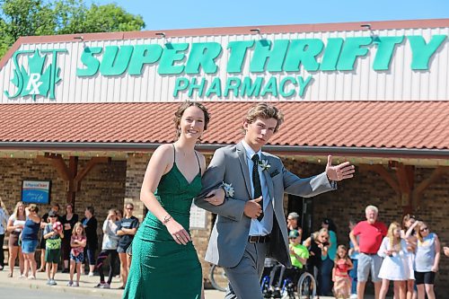 Rivers Collegiate students Alexis McLean and Nolan Perrault walk by the town’s Super Thrifty pharmacy during Friday’s graduate parade. (Kyle Darbyson/The Brandon Sun)