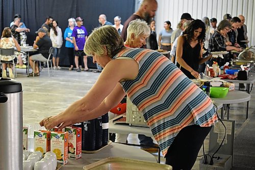 Mildred Zwarich who lived in Erickson and volunteered with the pancake breakfast, checked on juice supplies as a line of hungry attendees await their turn. (Geena Mortfield/The Brandon Sun)