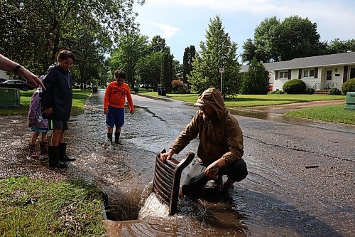 Residents opened drains to help relieve flooding on streets in Brandon's west end after heavy rains on Tuesday afternoon. (Photos by Tim Smith/The Brandon Sun)