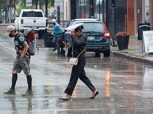 Mike Thiessen / Winnipeg Free Press 
Pedestrians shielding themselves from the rain downtown. 230627 &#x2013; Tuesday, June 27, 2023