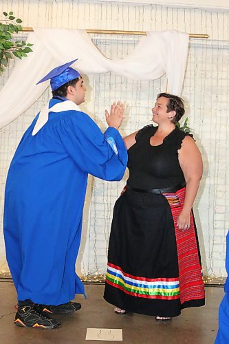 Graduate Russ Richard gives Prairie Hope High School staff member Raven Willoughby a high five after tracing her foot at The Firehall event venue on Thursday morning. Prairie Hope will use this drawing to make Willoughby some commemorative moccasins, since she is leaving the school to fulfil another position in the Brandon School Division starting this fall. (Kyle Darbyson/The Brandon Sun)