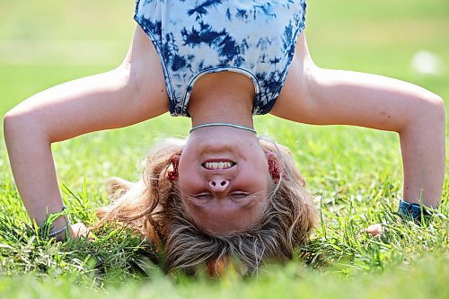 Aurora McMurachy hangs upside down while working out at the Riverbank Discovery Centre outdoor fitness equipment in Brandon on a hot Monday. (Tim Smith/The Brandon Sun)