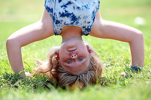 03072023
Aurora McMurachy hangs upside down while working out at the Riverbank Discovery Centre outdoor fitness equipment in Brandon on a hot Monday.
(Tim Smith/The Brandon Sun)