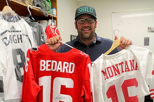 Brandon University athlete services and events co-ordinator Tyler Crayston holds signed Connor Bedard and Joe Montana jerseys, which are up for grabs at the Bobcats BIRT Cup golf tournament this Friday. (Thomas Friesen/The Brandon Sun)