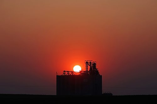 The sun sets west of a grain terminal near Boissevain on a warm and clear Monday evening. (Tim Smith/The Brandon Sun)