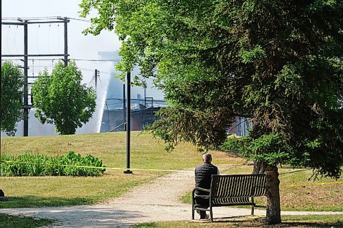 MIKE DEAL / WINNIPEG FREE PRESS
A man watches as WFPS crews try to douse a large fire in the block on the southwest corner of Sutherland Avenue and Maple Street North Tuesday morning. 
230704 - Tuesday, July 4, 2023. 
