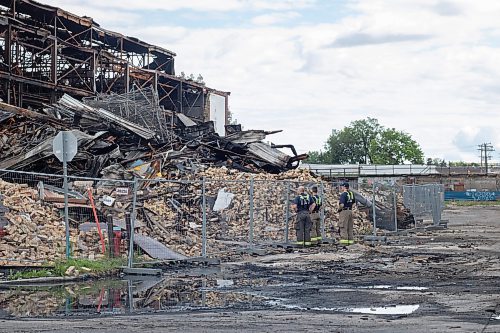 Mike Thiessen / Winnipeg Free Press 
A fire crew surveys the gargantuan pile of rubble at the site of Tuesday&#x2019;s warehouse fire in Point Douglas. 230705 &#x2013; Wednesday, July 5, 2023