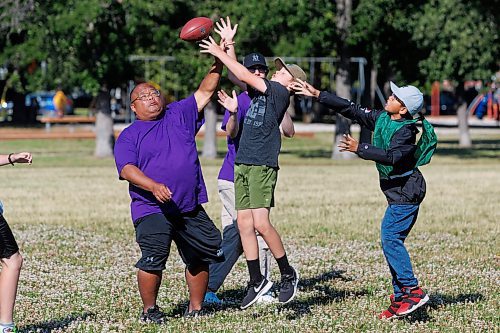 MIKE DEAL / WINNIPEG FREE PRESS
Sports camp leader, AJ Juan (left), blocks the ball from the hands of Charlie Myers (centre) while opponent in the green pinny, Lei Zhuang (right) during a touch football scrimmage at Flag Football camp at Notre Dame Recreational Centre Thursday morning. 
230706 - Thursday, July 06, 2023.