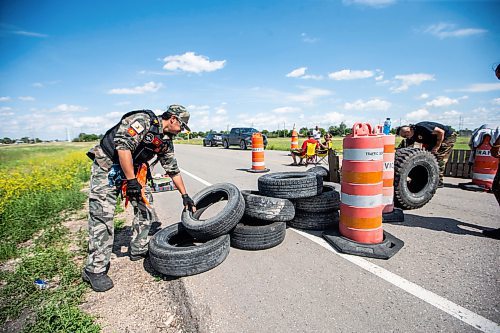 MIKAELA MACKENZIE / WINNIPEG FREE PRESS

Darrell Fontaine rebuilds a blockade closing off Brady Landfill after letting a vehicle through on Thursday, July 6, 2023.  For Chris Kitching story.
Winnipeg Free Press 2023.