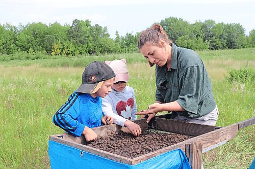 Brandon University student Arynn Woytkiw shows some local visitors the proper method of sifting through dirt to find historical artefacts during Saturday morning's tour of a dig site located 15 kilometres south of Melita. (Kyle Darbyson/The Brandon Sun) 