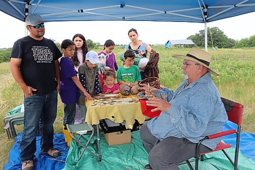 Gary Wowchuk demonstrates the proper way to manufacture stone tools in front of a family that's dropped by to tour an archeological dig site that was first established south of Melita in 2019. (Kyle Darbyson/The Brandon Sun) 