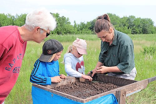Brandon University student Arynn Woytkiw shows some local visitors the proper method of sifting through dirt to find historical artefacts during Saturday morning's tour of a dig site located 15 kilometres south of Melita. (Kyle Darbyson/The Brandon Sun) 
