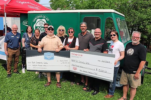 Members of the Park Community Centre, alongside other Brandon residents like city councillor Kris Desjarlais and school board trustee Duncan Ross, accept two cheques worth a total of $100,000 from representatives of Heritage Co-op during Sunday's free barbecue in the city's downtown core. (Kyle Darbyson/The Brandon Sun)