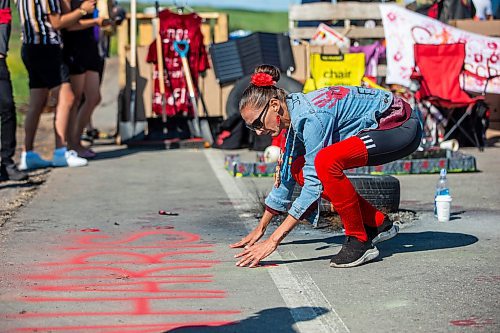 MIKAELA MACKENZIE / WINNIPEG FREE PRESS

Diane Bousquet puts red hand prints down at the Brady Road blockade on Monday, July 10, 2023.  For Chris Kitching story.
Winnipeg Free Press 2023.