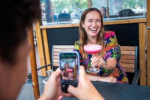 MIKAELA MACKENZIE / WINNIPEG FREE PRESS

Josh Goossen takes a photo of Lily Medynska and her Malibu Barbie cocktail at the Amsterdam Tea House on Wednesday, July 12, 2023.  For AV Kitching story.
Winnipeg Free Press 2023.