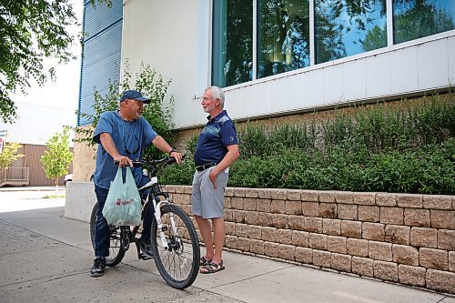 Brandon West candidate hopeful Quentin Robinson speaks with passing cyclist Leon Richels outside the YMCA building on Princess Avenue on Thursday afternoon. Robinson is seeking the NDP nomination in Brandon West for the upcoming 2023 provincial election. (Matt Goerzen/The Brandon Sun)