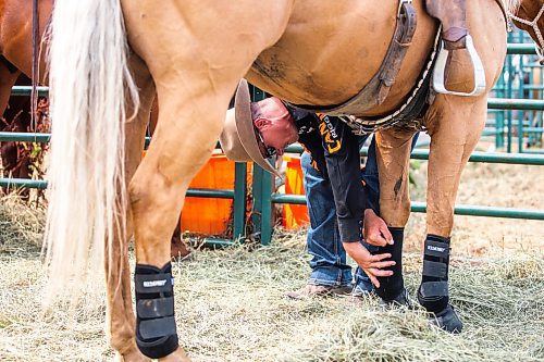MIKAELA MACKENZIE / WINNIPEG FREE PRESS

Tyler Thomson, pick-up man, puts splint and bell boots onto his horses before the start of the rodeo at the Manitoba Stampede in Morris on Saturday, July 22, 2023. For Tyler story.
Winnipeg Free Press 2023