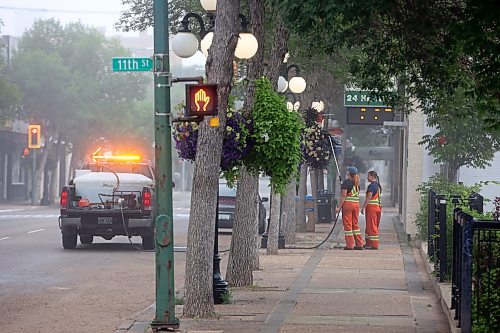 26072023
City of Brandon workers water hanging flower baskets along Rosser Avenue in Brandon on a foggy Wednesday morning. (Tim Smith/The Brandon Sun)