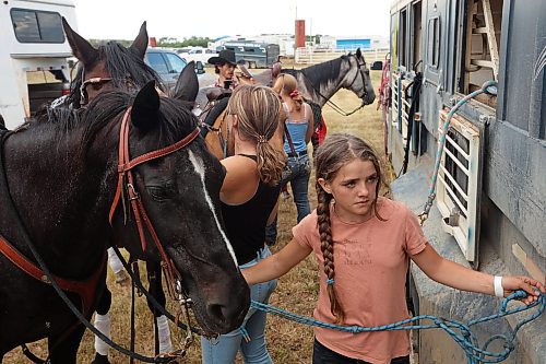 27072023
Lissie Bouer (R) gets horses ready with her sisters before performing in the grand entry and national anthems during the first go-round of the Manitoba Threshermen&#x2019;s Reunion and Stampede rodeo near Austin, Manitoba on Thursday evening.  (Tim Smith/The Brandon Sun)