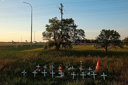 A memorial to the June 15 collision between a bus and a semi-truck that claimed the lives of 17 passengers sits just south of the intersection of the Trans-Canada Highway and Highway 5 as RCMP officers and tow truck operators work at the scene of a three-vehicle collision at the same intersection on Monday evening. Three people involved were taken to hospital. (Tim Smith/The Brandon Sun)