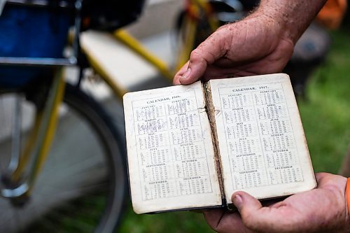 MIKAELA MACKENZIE / WINNIPEG FREE PRESS

Mic Whitty, who is on his eighth year of cycling around the world visiting every cemetery where a Commonwealth World War One or Two causality is buried, shows his grandfather&#x573; diary (which inspired the trip) at the St. Boniface Cathedral cemetery on the cross-Canada leg of his journey on Tuesday, Aug. 1, 2023. For Cierra Bettens story.
Winnipeg Free Press 2023