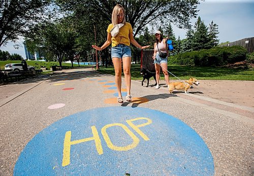 JOHN WOODS / WINNIPEG FREE PRESS
Kayla Houston hops as her friends, Amber Bosko, 
Wilson the Corgi, and Gabby the Lab look on as they use a walkway which is part of the Play At The Forks program at The Forks in Winnipeg, Tuesday, August 1, 2023. 

Reporter: