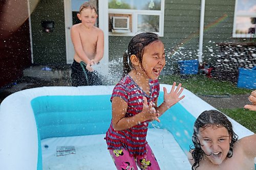 Angel Tacan (middle) and Cyrus Enns (right) react to being sprayed with water by Huxley Vanasse-Vanjaarsveld (left) while a group of friends play in an inflatable pool in Brandon’s east end on a scorching hot Wednesday. (Tim Smith/The Brandon Sun)