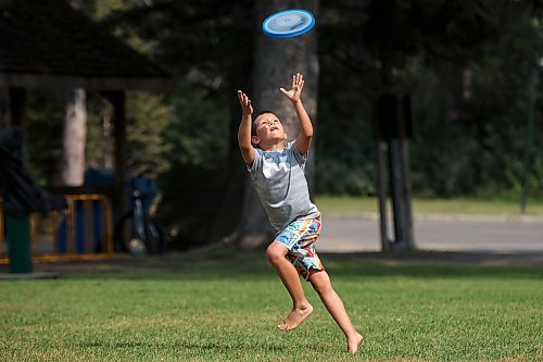 Madden Dyck, 8, runs to catch a frisbee while playing with his dad and a family friend in Wasagaming on a hot Thursday. 
(Tim Smith/The Brandon Sun)