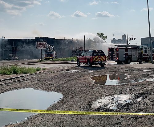 By the late aftertoon, three fire trucks were stationed at the scene as crews continued hosing down the building on the 900 block of Logan Avenue. August. 6, 2023. (Cierra Bettans / Winnipeg Free Press)